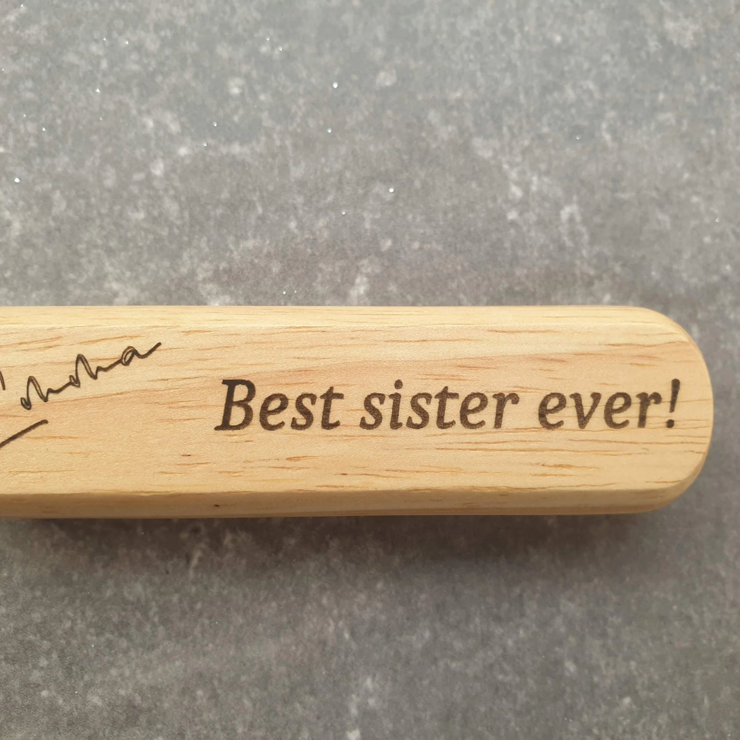 Wooden engraved bottle opener with 'Best sister ever!' engraving on a gray background