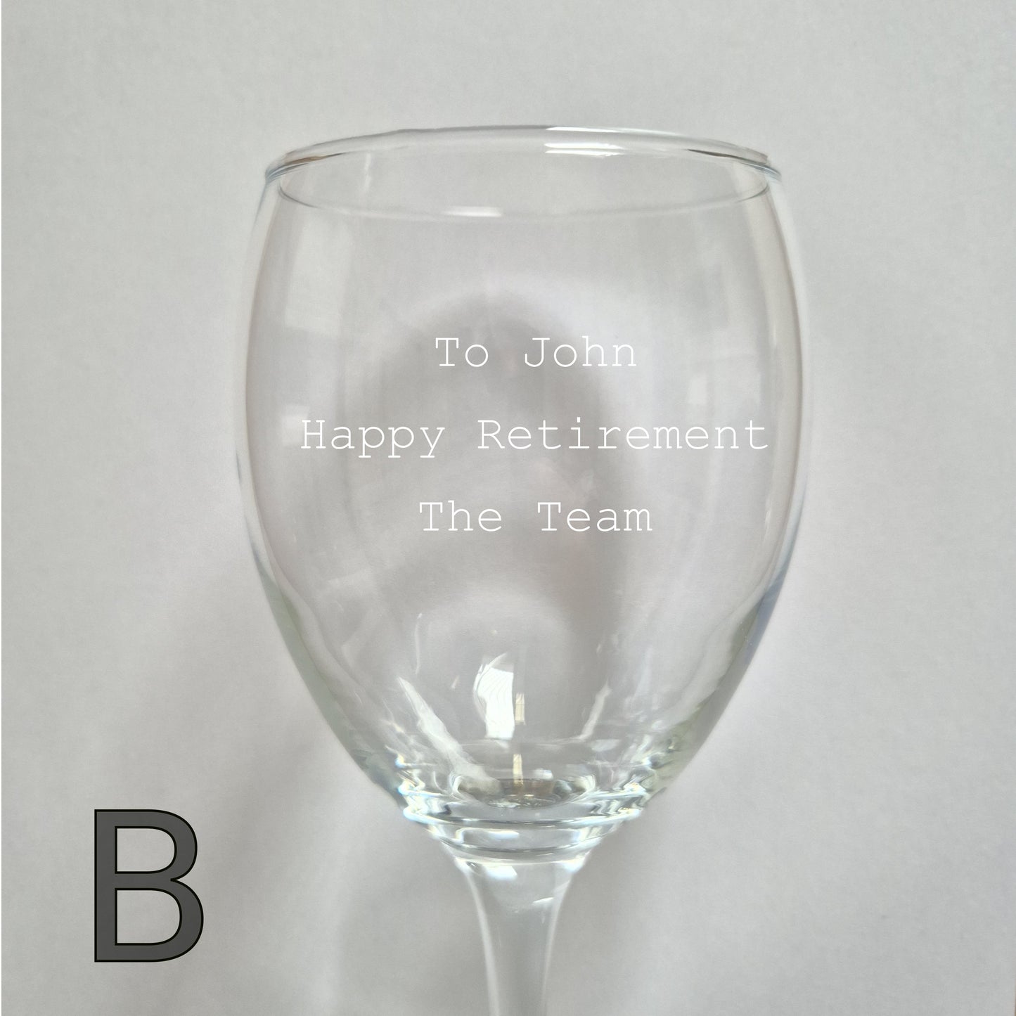 Personalised wine glass with engraved text on a light gray background