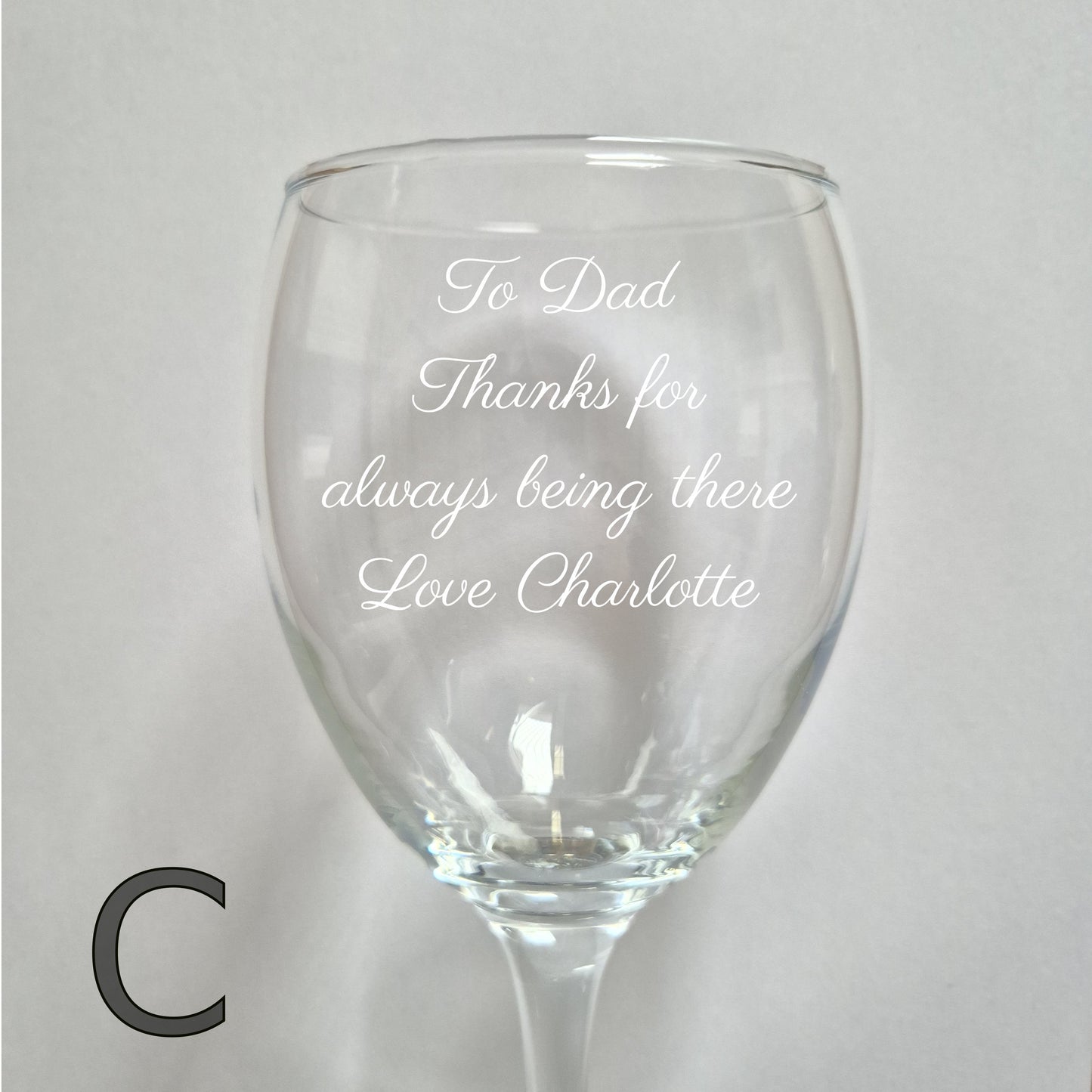 Personalised wine glass with engraved message on a light gray background