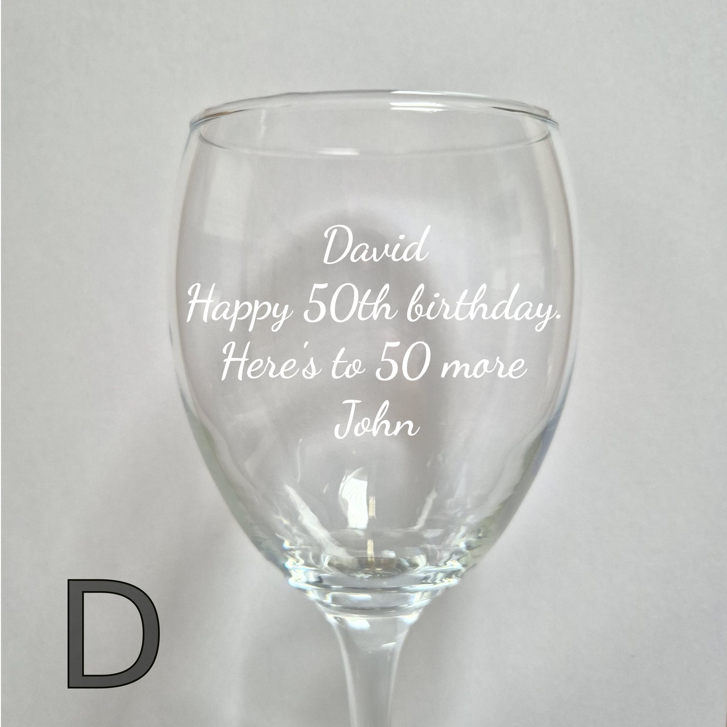 Personalised wine glass with engraved birthday message on a light gray background