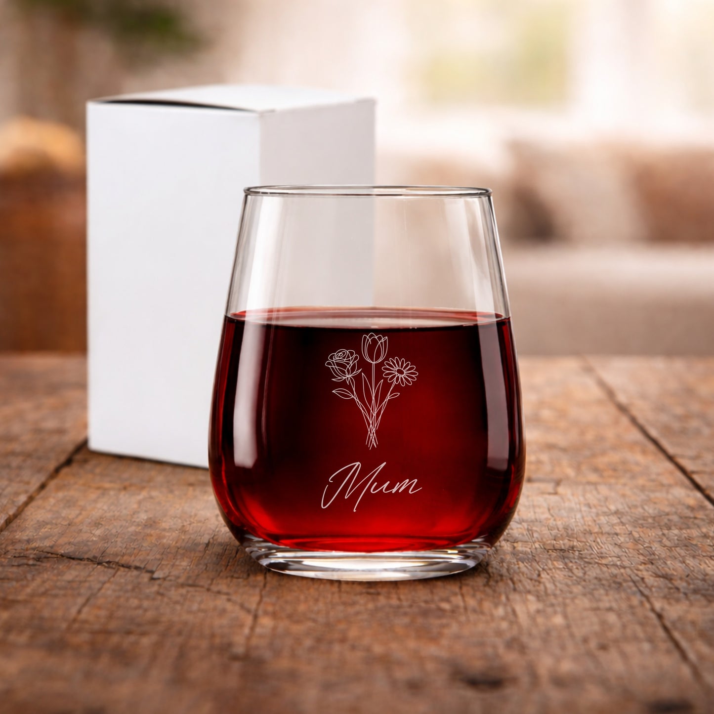 Glass of red wine with 'Mum' and floral design on a wooden surface