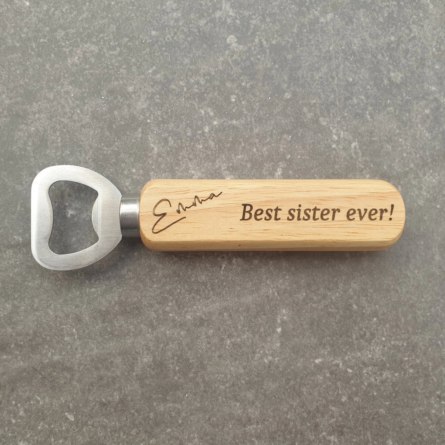 Bottle opener with wooden handle and engraved text on a gray surface