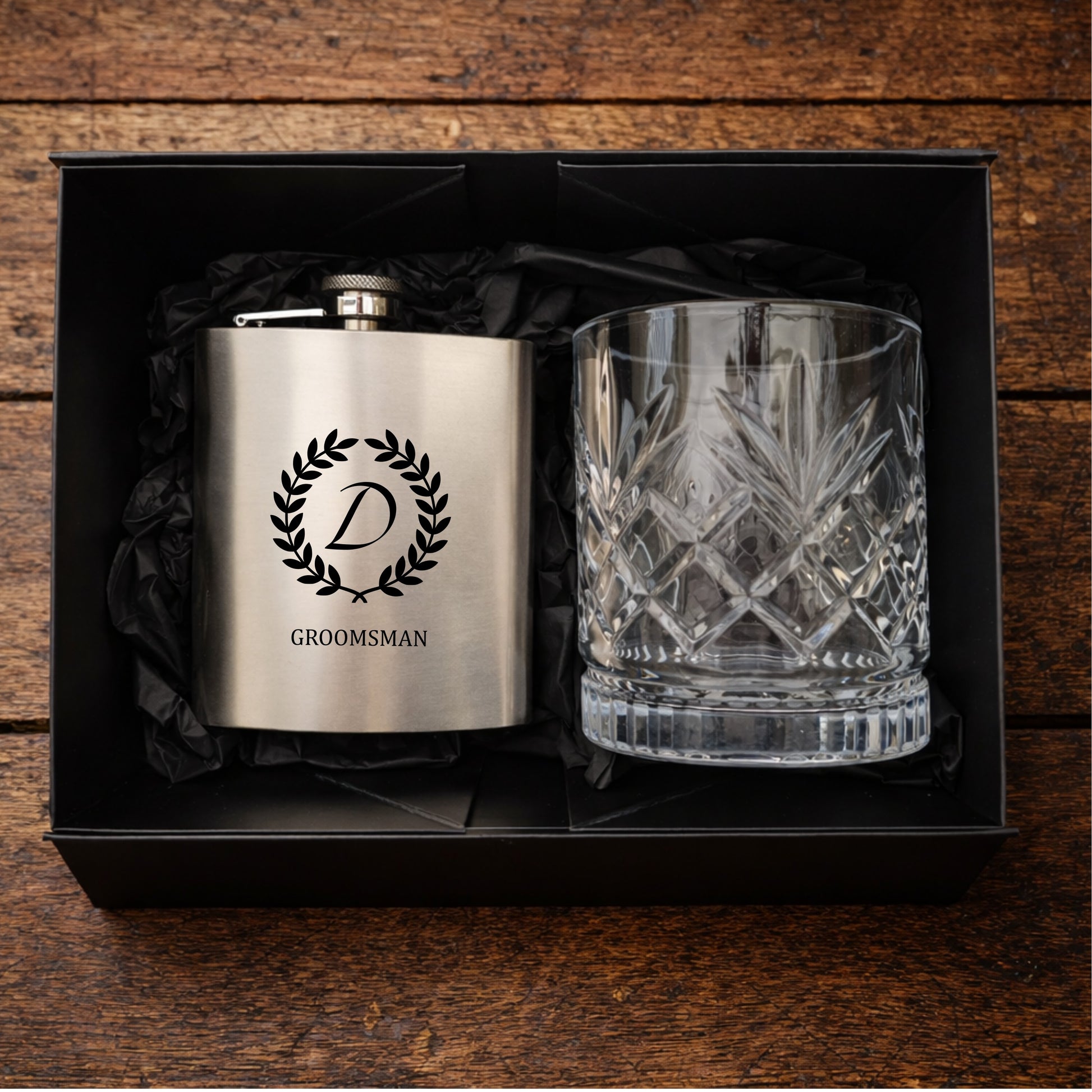 Silver flask and crystal glass in a black box on a wooden surface