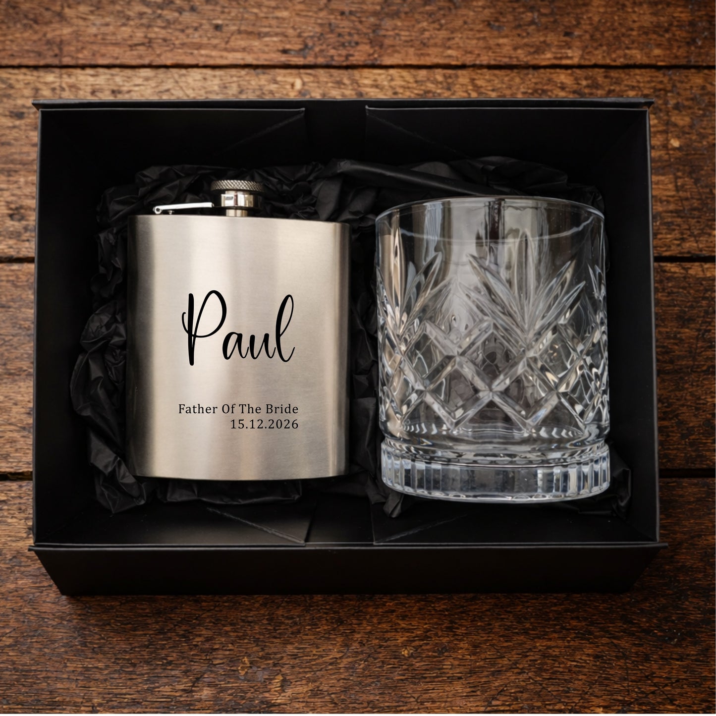 Personalised hip flask and glass set in a black box on a wooden surface
