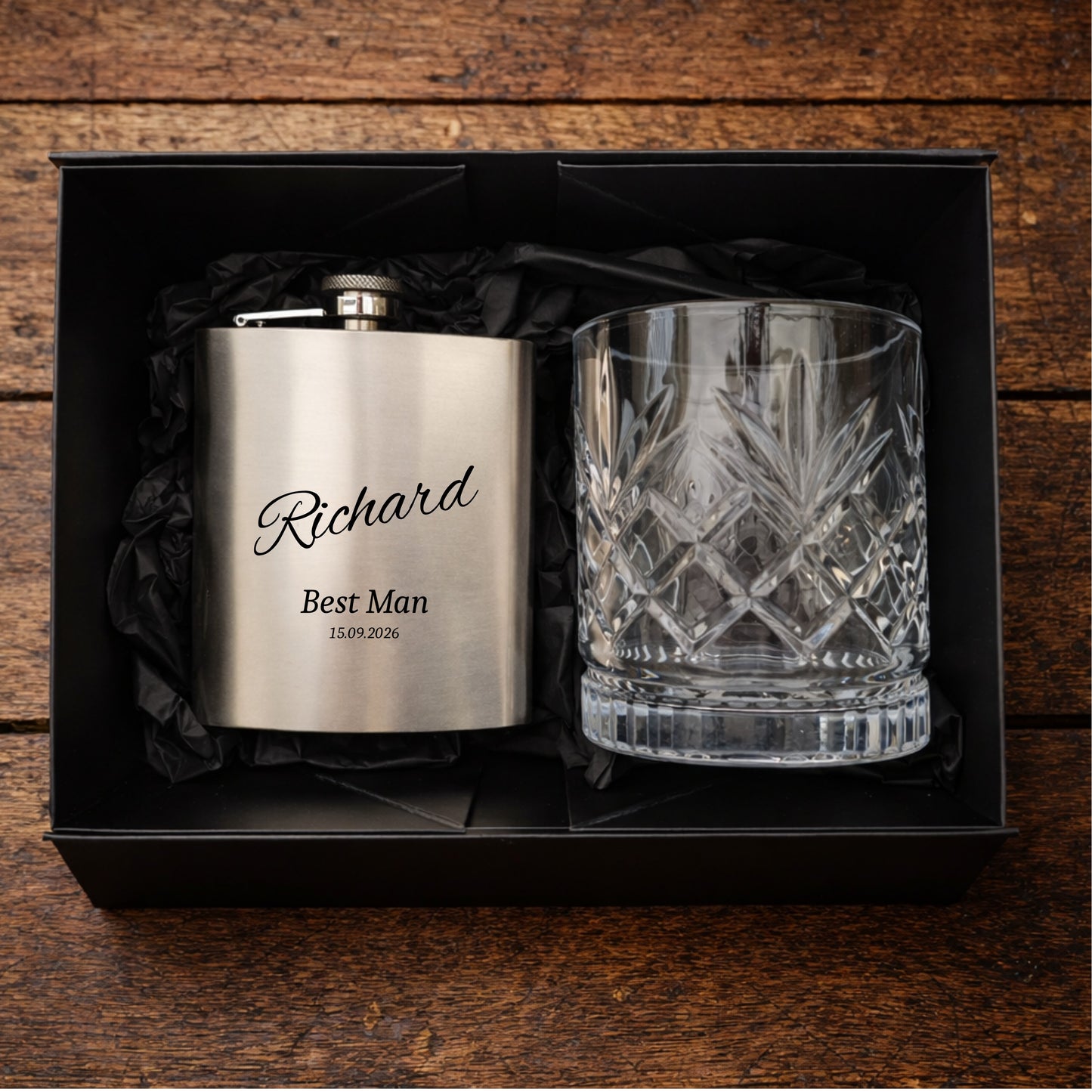 Stainless steel flask and crystal glass in a black box on a wooden surface