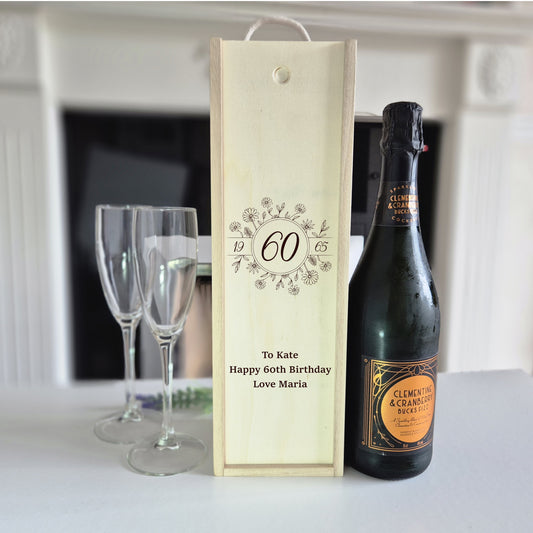 60th birthday champagne bottle box next to a bottle and 2 glasses