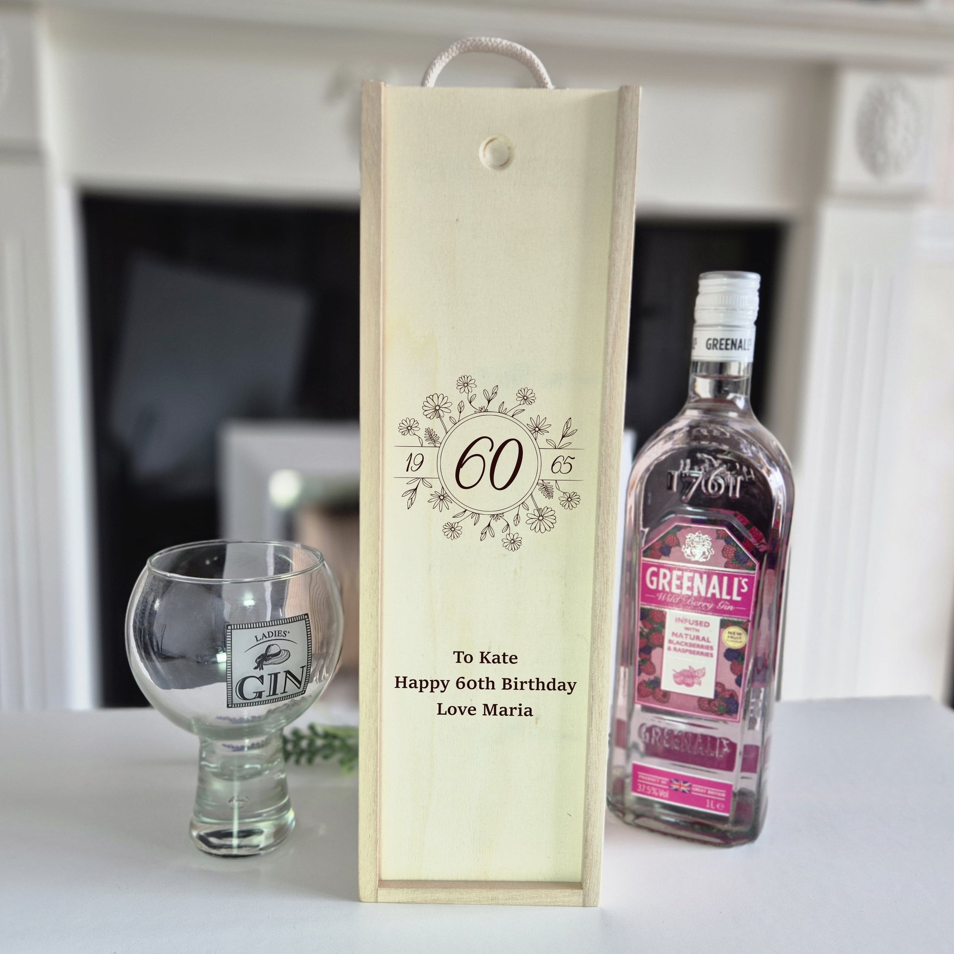 60th birthday champagne bottle box next to a bottle of gin and 1 glass