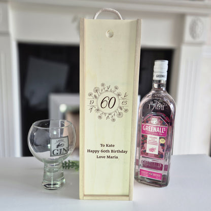 60th birthday champagne bottle box next to a bottle of gin and 1 glass