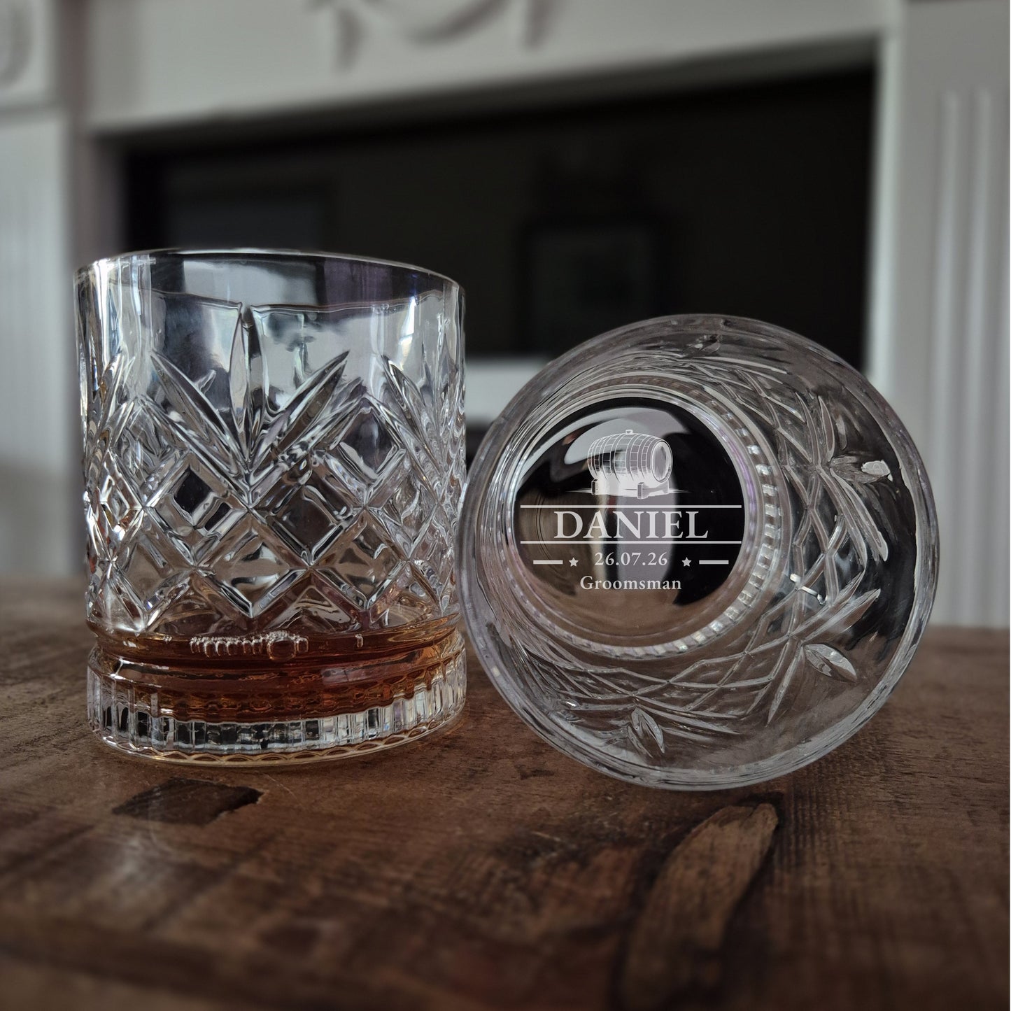 Two crystal glasses with engraved names on a wooden surface