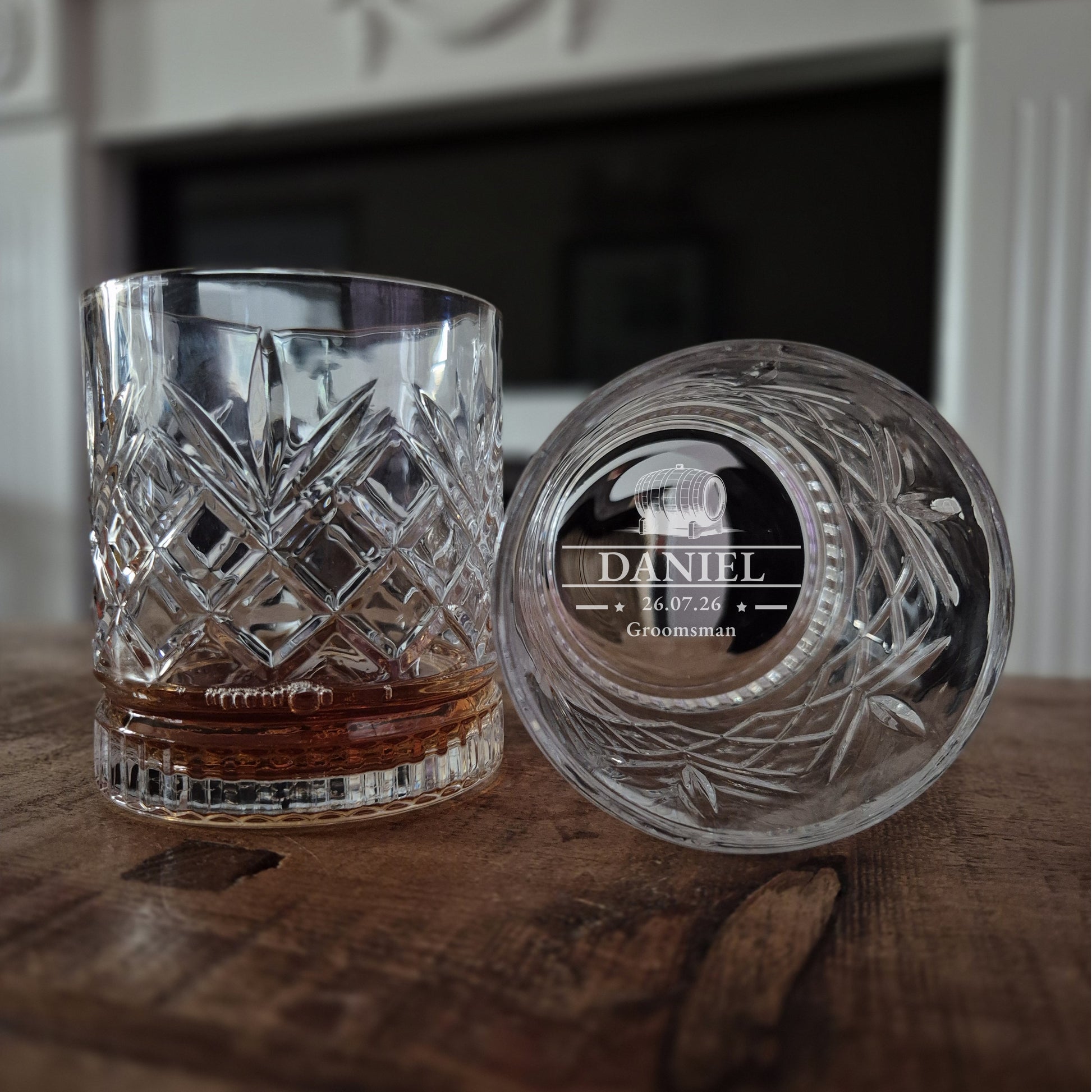 Two crystal glasses with engraved names on a wooden surface