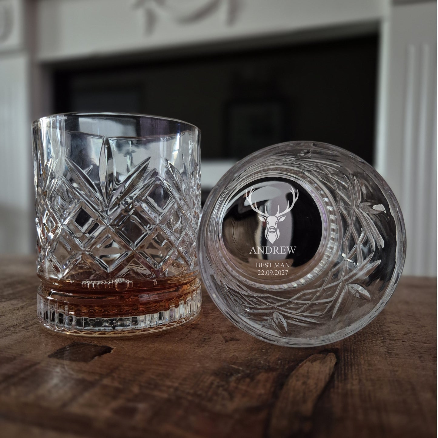 Cut crystal glass tumbler with engraved base on a wooden surface