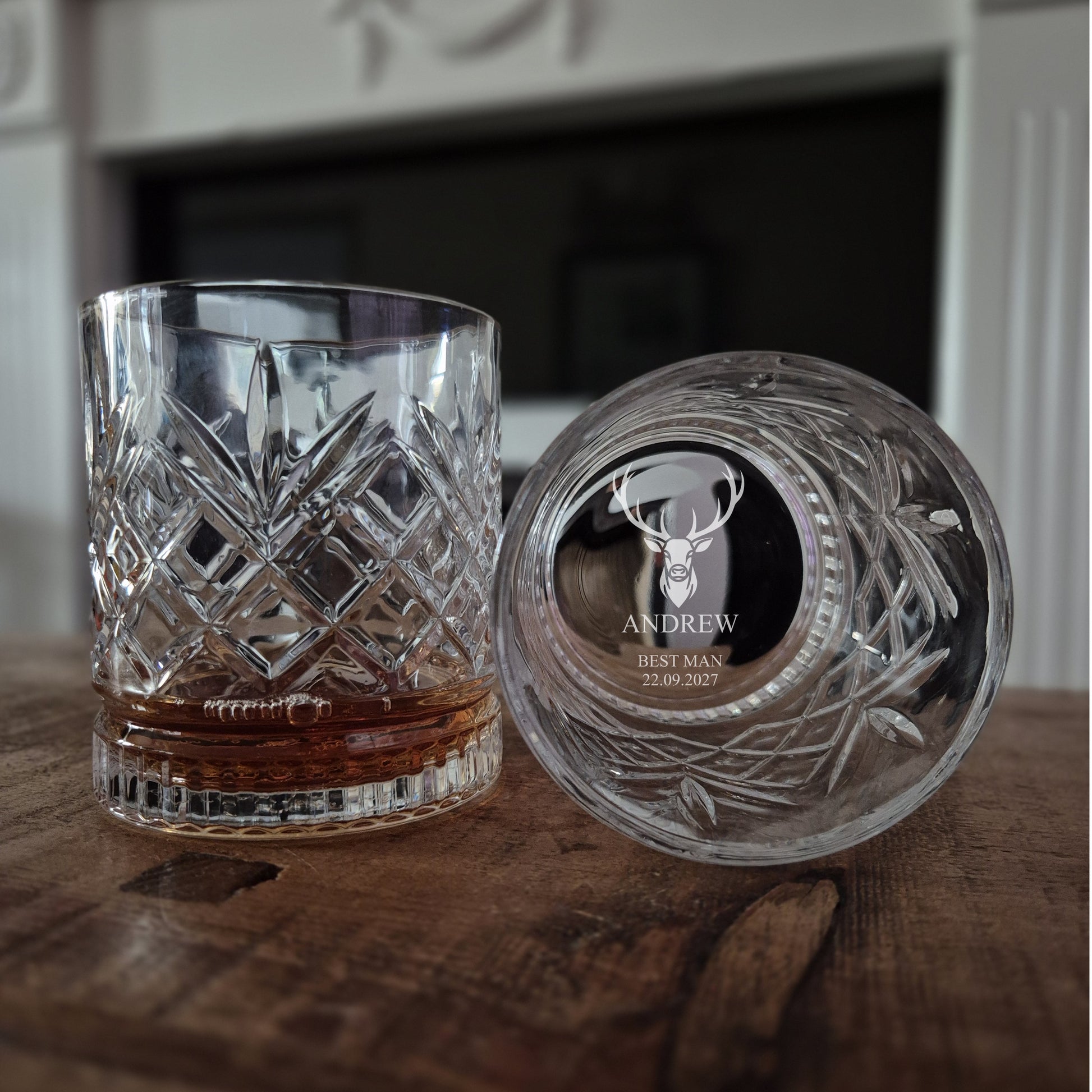 Cut crystal glass tumbler with engraved base on a wooden surface