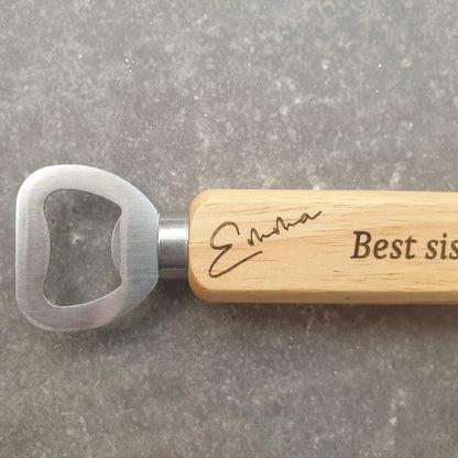 Bottle opener with wooden handle and engraved text on a gray surface