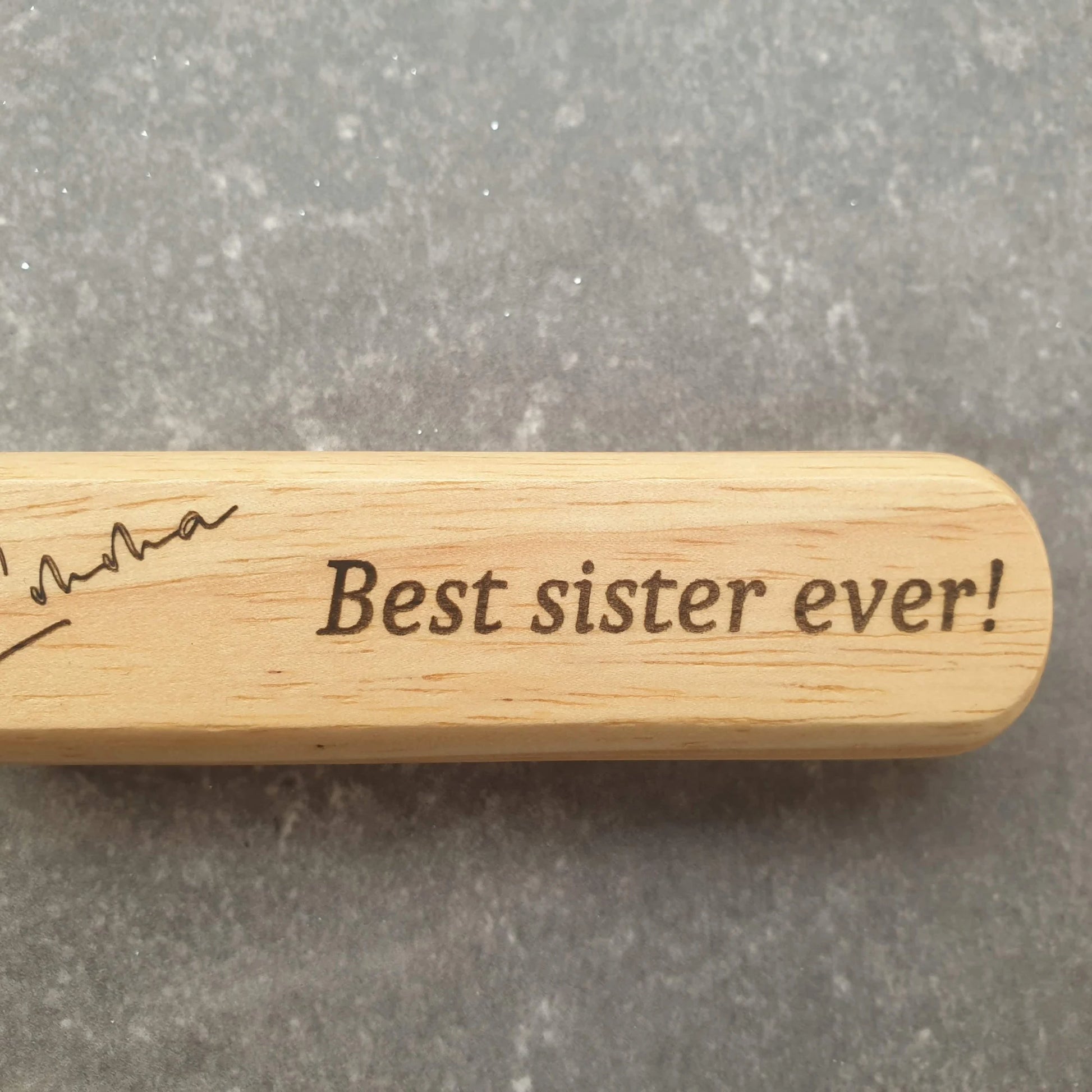 Wooden engraved bottle opener with 'Best sister ever!' engraving on a gray background