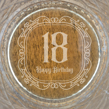 The base of a personalised whisky glass with '18 Happy Birthday' engraving on a glass surface