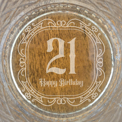 The base of a personalised whisky glass with '21 Happy Birthday' engraving on a glass surface