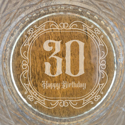 The base of a personalised whisky glass with '30 Happy Birthday' engraving on a glass surface