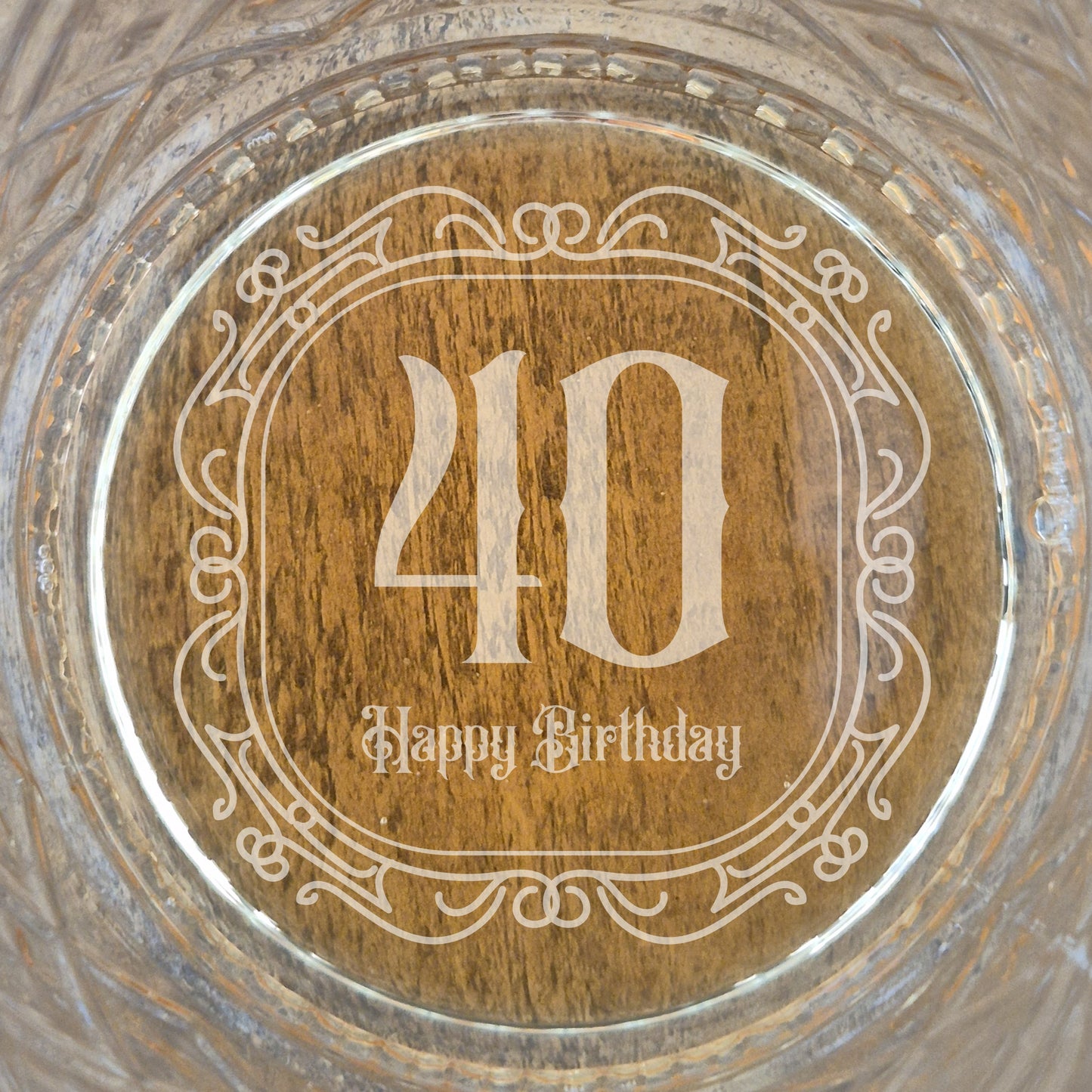 The base of a personalised whisky glass with '40 Happy Birthday' engraving on a glass surface