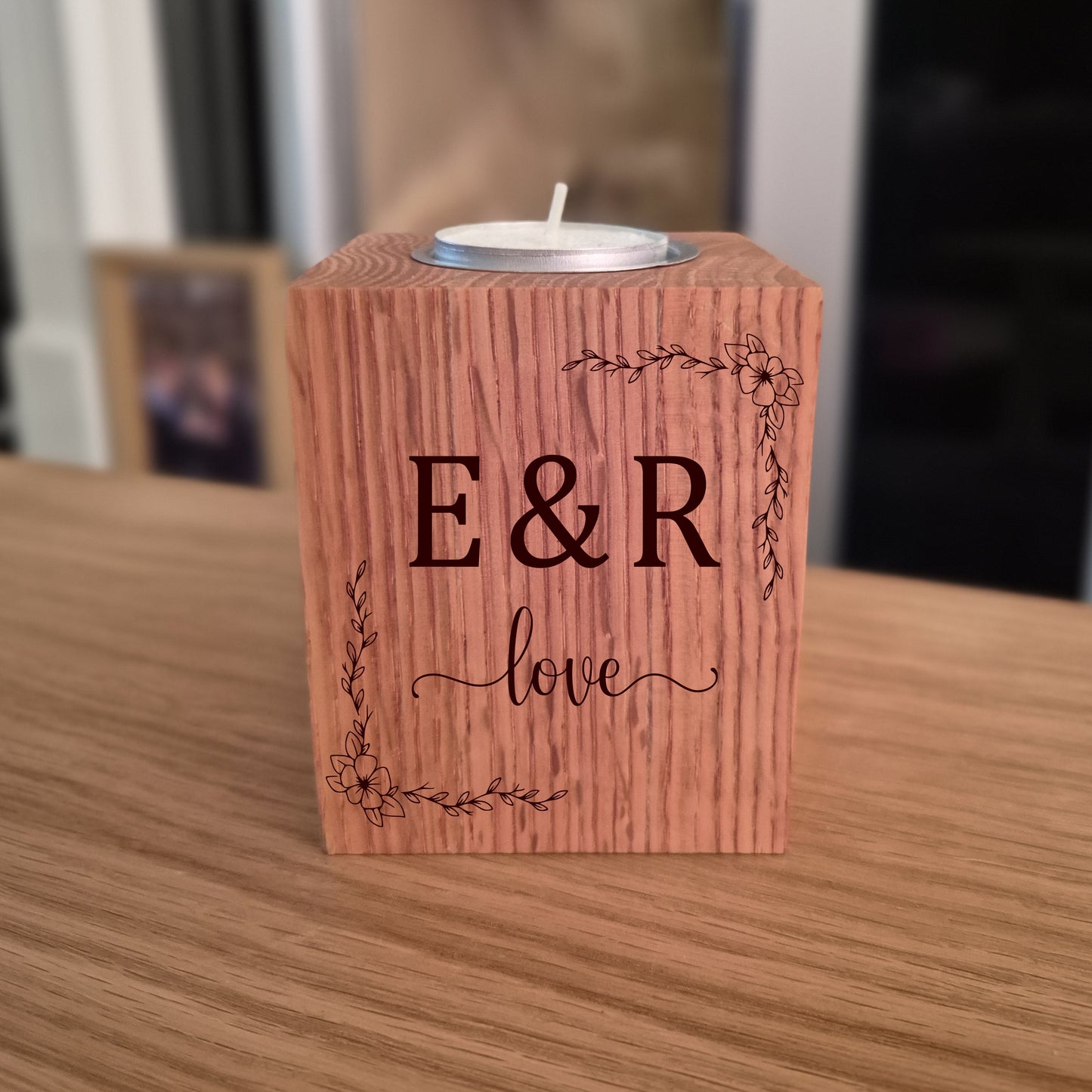 Oak tealight holder with engraved initials 'E&R' and the word 'love', placed on a wooden surface.