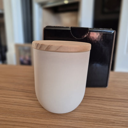 White jar containing soy candle with wooden lid.