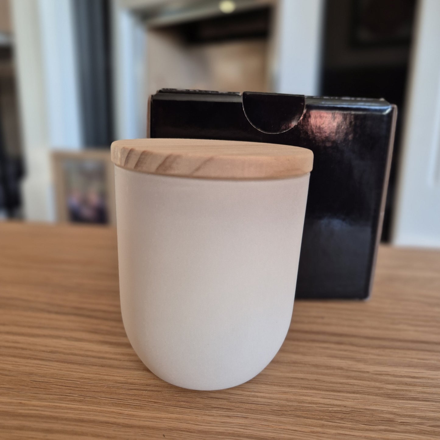 Soy candle with gift box on a wooden surface.
