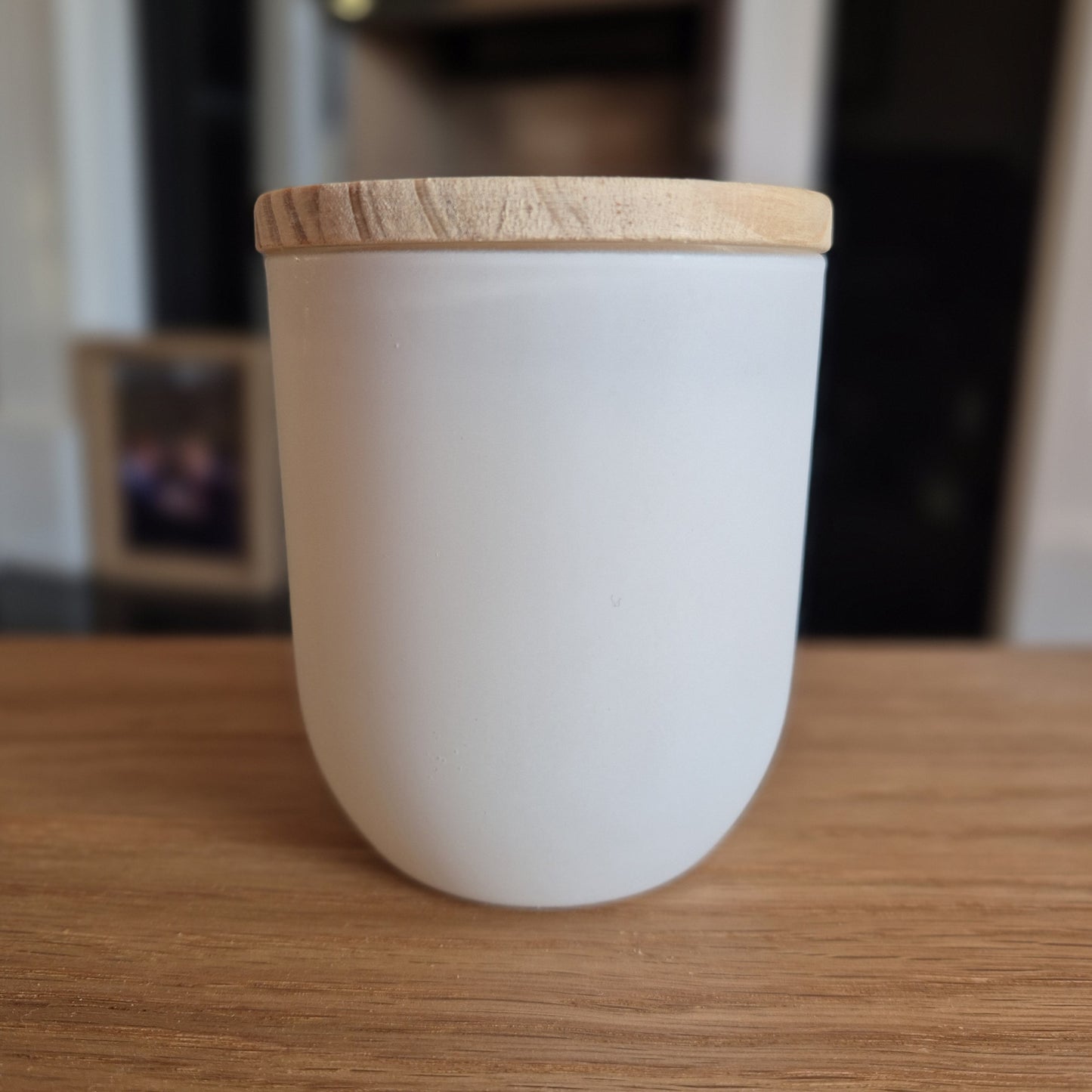 White jar containing soy candle with wooden lid.
