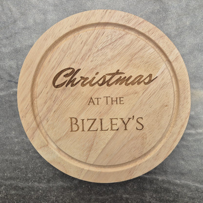 Personalised cheese board with engraved text 'Christmas at The Bizley's' on a gray surface