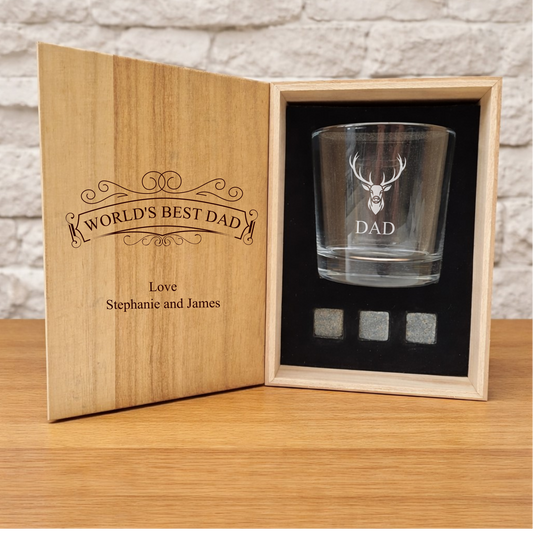 Glass with engraved design in a wooden box labeled 'World's Best Dad' on a wooden surface.