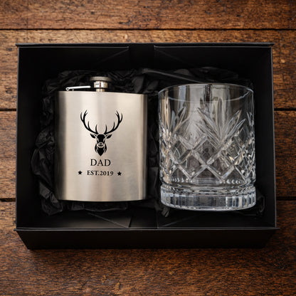 Silver flask with deer design and glass in a black box on a wooden background