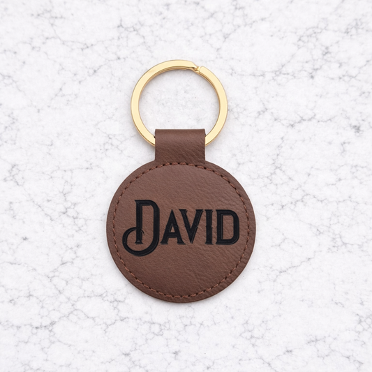 Brown leather keychain with 'DAVID' engraving on a light gray textured background