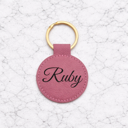 Pink leather keychain with 'Ruby' engraving on a textured white background