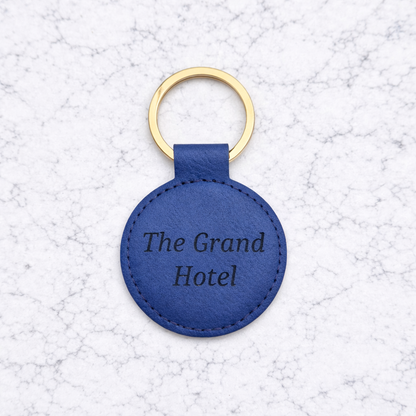 Blue leather keychain with 'The Grand Hotel' text on a textured white background
