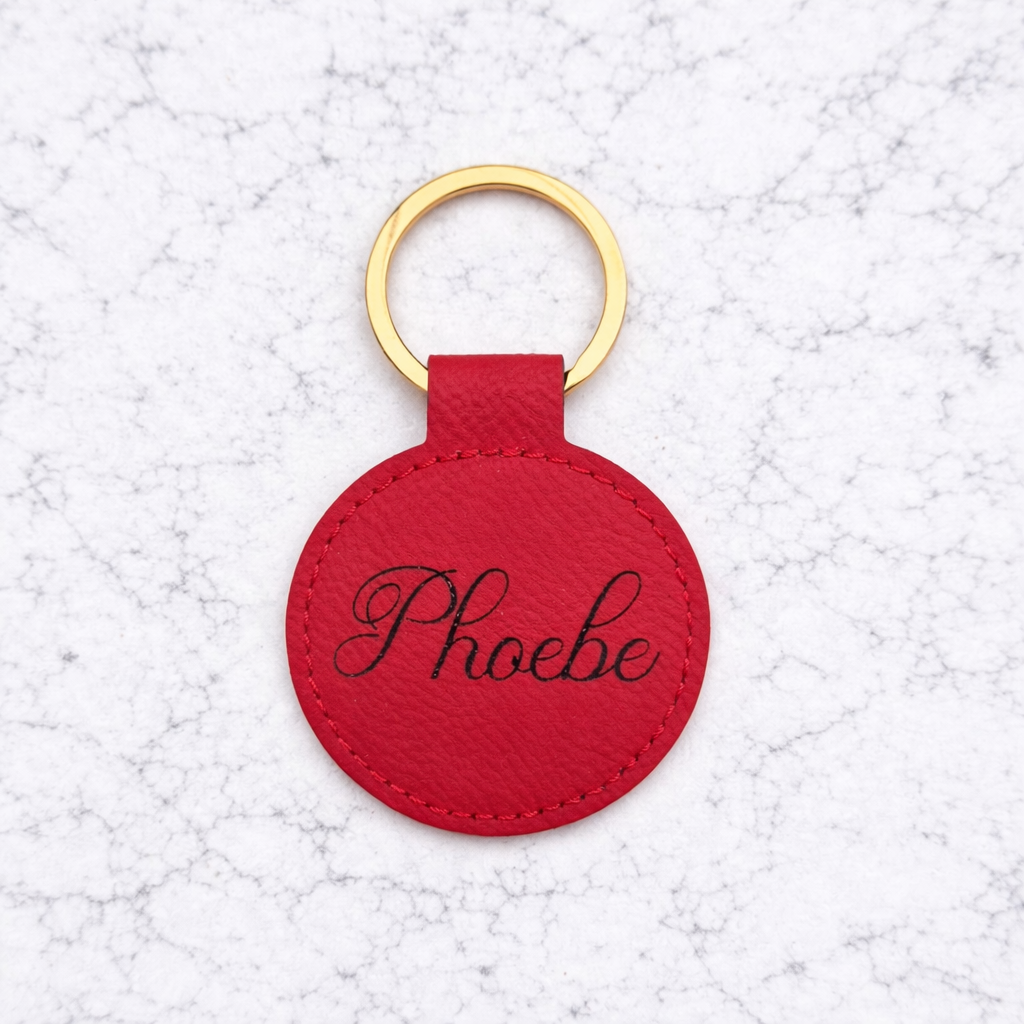 Red round keychain with 'Phoebe' engraving on a textured white background