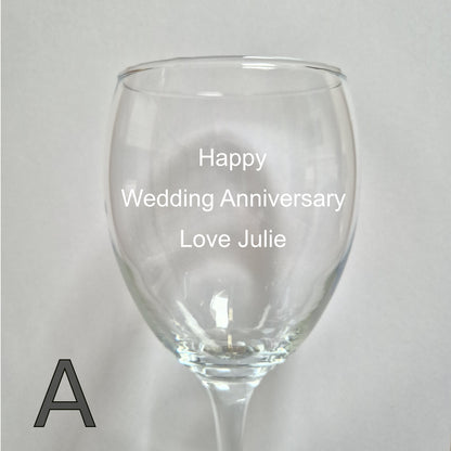 Personalised wine glass with 'Happy Wedding Anniversary Love Julie' text on a light gray background