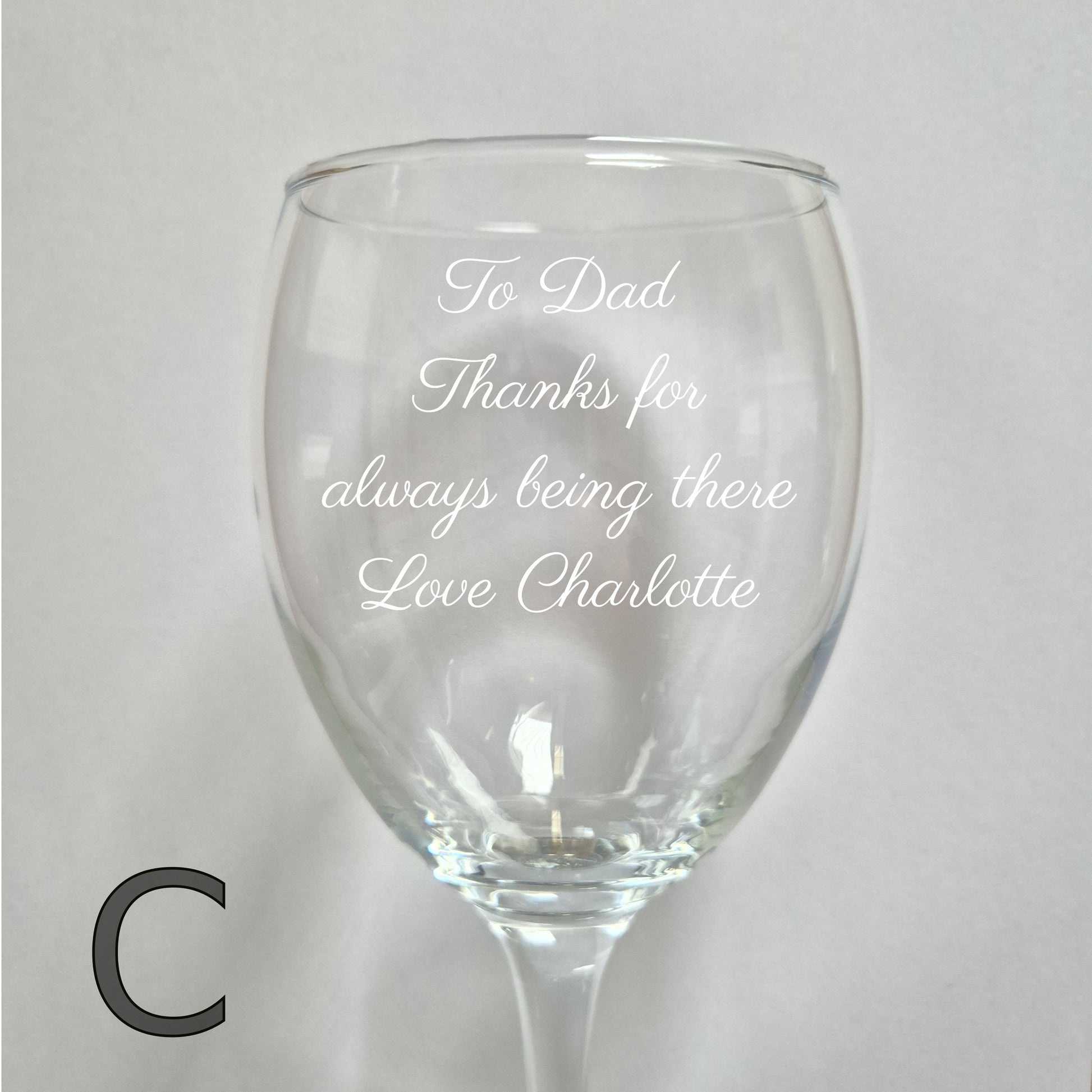 Personalised wine glass with engraved message on a light gray background