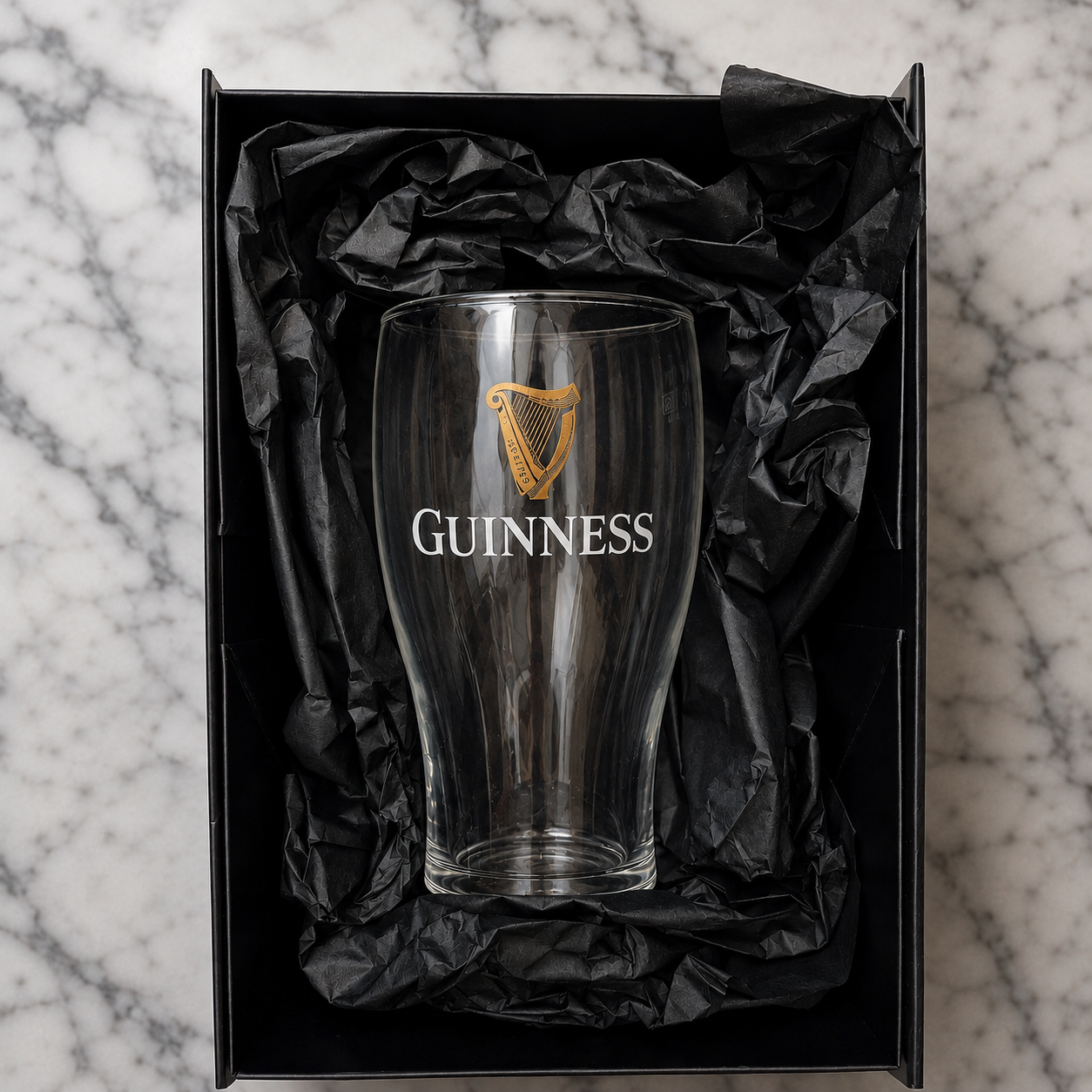 Guinness glass in a black gift box on a marble surface