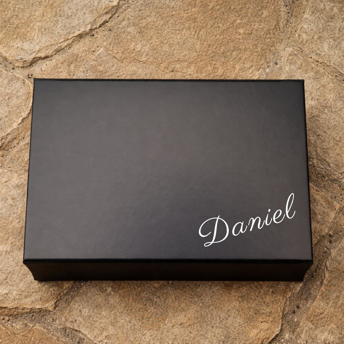 Black box with 'Daniel' on it against a stone wall background