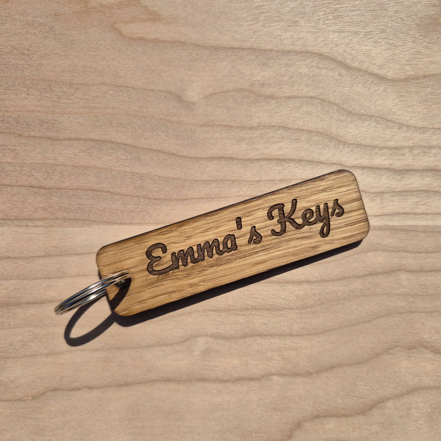 Oak keyrings measureing 90 x 25 x 4mm. Each keyring is engraved in a different font. This keyring says emmas keys.