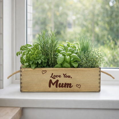 Wooden planter box with herbs and 'Love You, Mum' engraving on a windowsill.