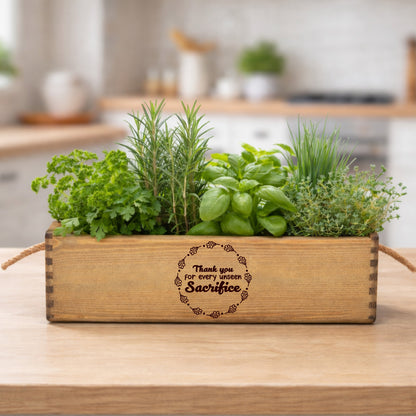 Wooden planter box with herbs on a kitchen counter, engraved message 'Thank you for every little sacrifice'.