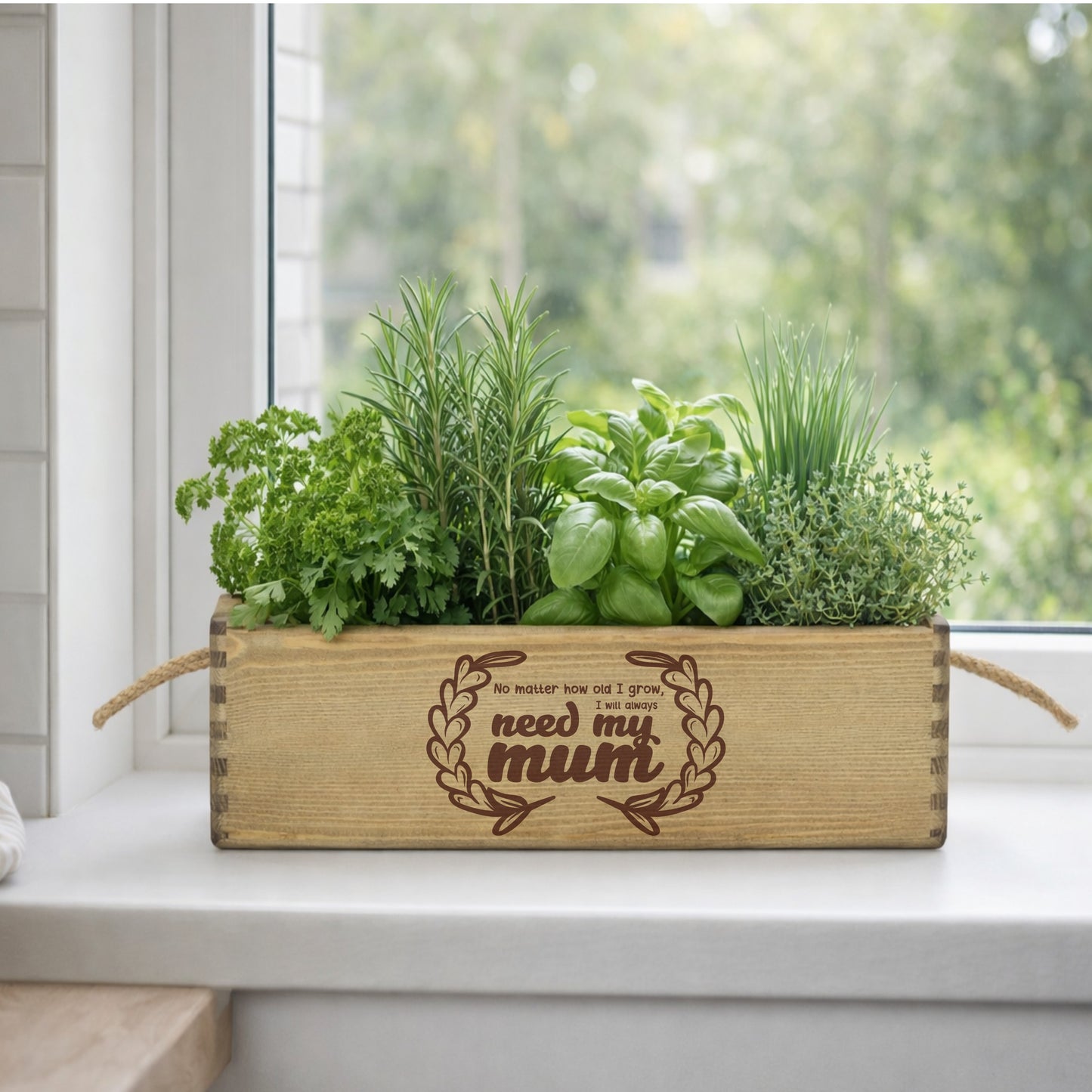 Wooden planter box with herbs on a windowsill, engraved with 'No matter how far I grow, I need my mum'.