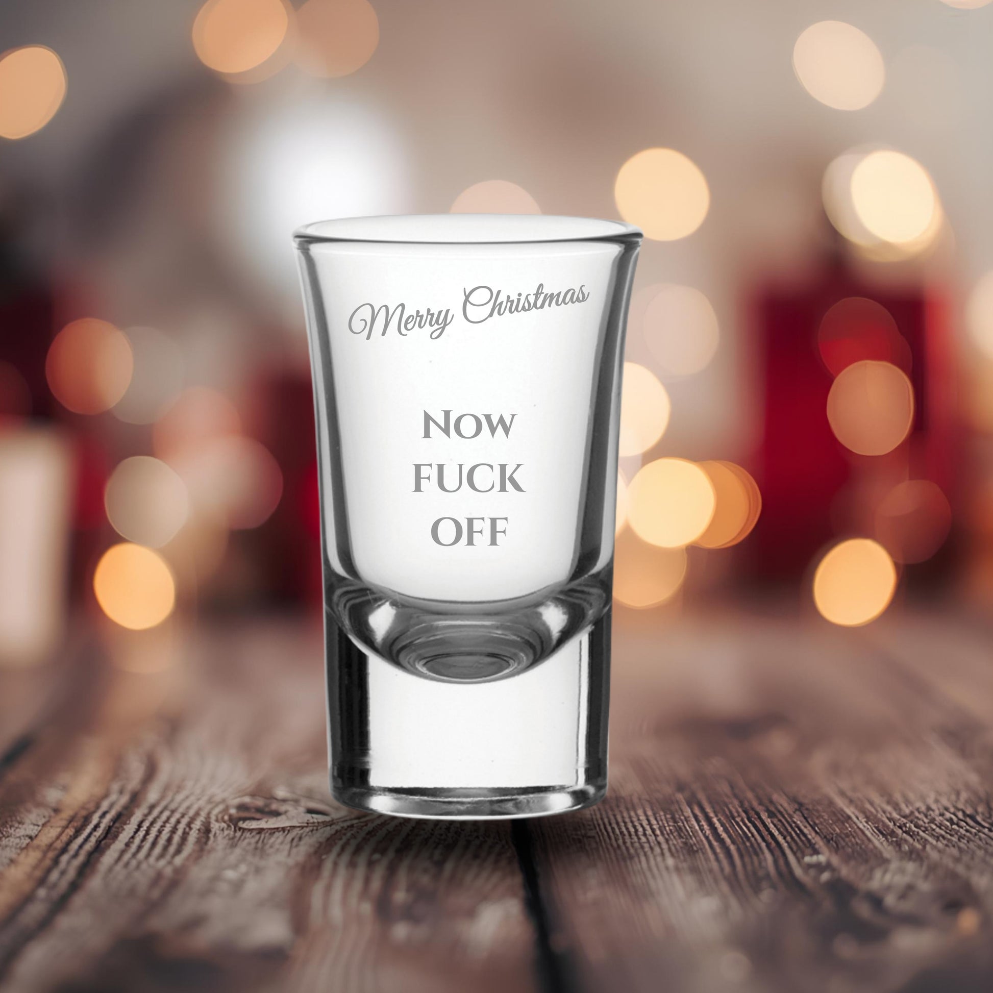 Glass with printed text on a wooden surface with blurred lights in the background