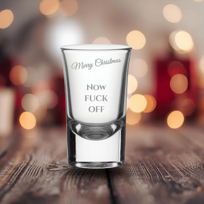 Glass with printed text on a wooden surface with blurred lights in the background