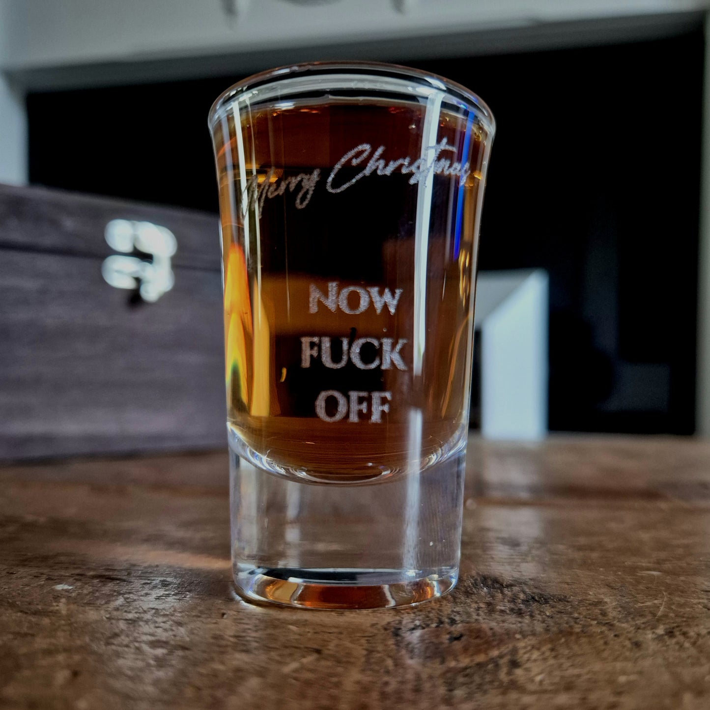Clear shot glass with printed text on a wooden surface