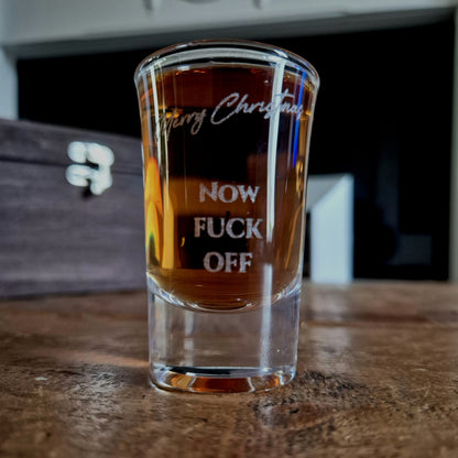 Clear shot glass with printed text on a wooden surface