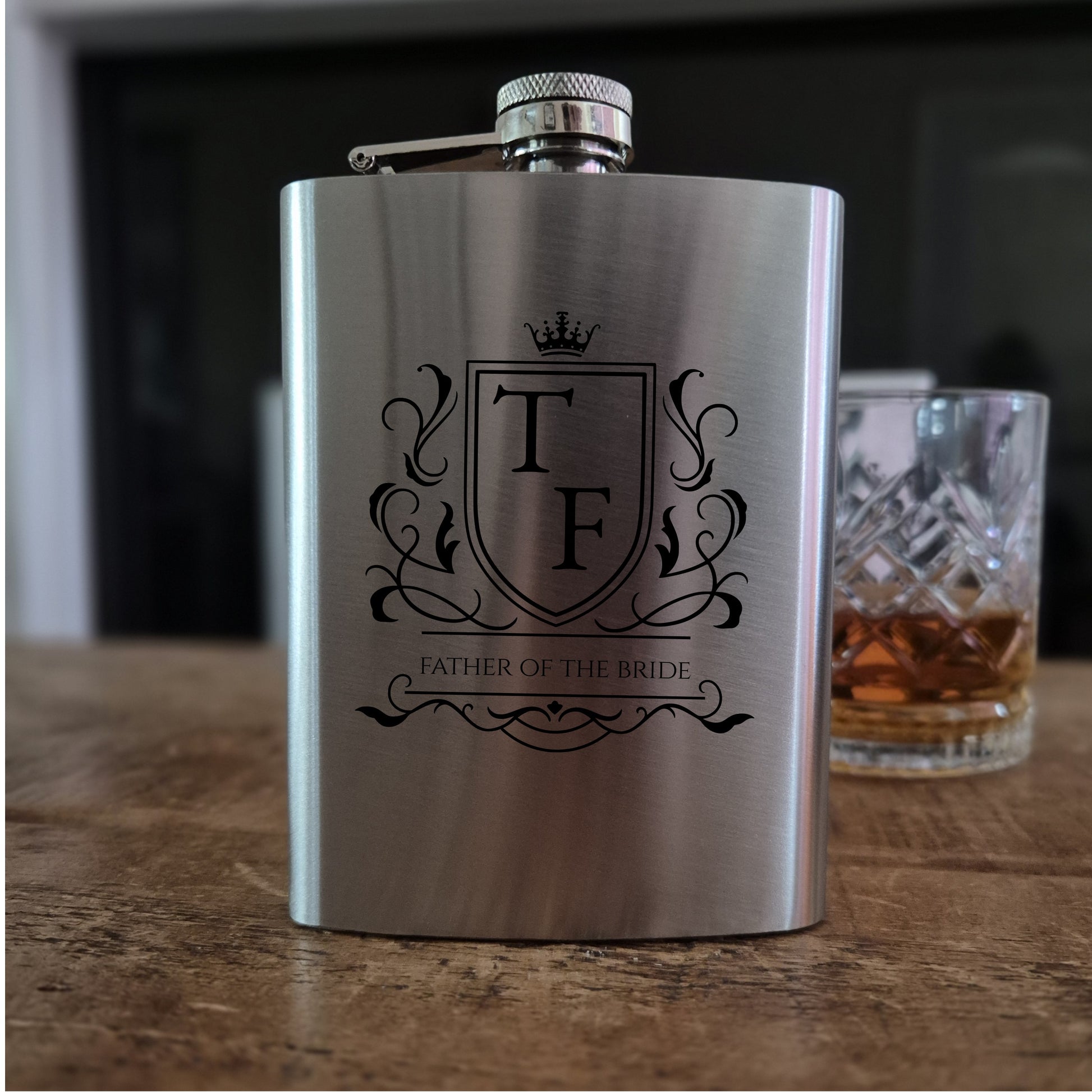 Personalised hip flask Stainless steel  with 'Best Man' engraving on a wooden surface with a glass of whiskey in the background.