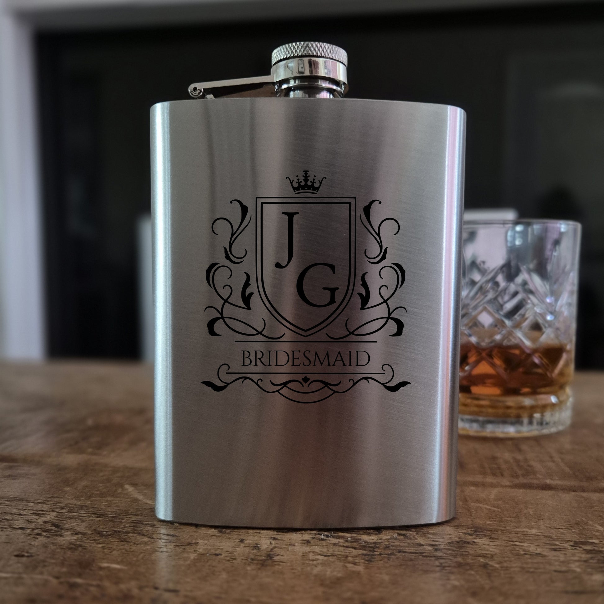 Personalised hip flask Stainless steel  with 'Best Man' engraving on a wooden surface with a glass of whiskey in the background.