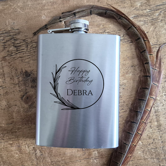 Silver flask with 'Happy Birthday Debra' engraving on a wooden surface