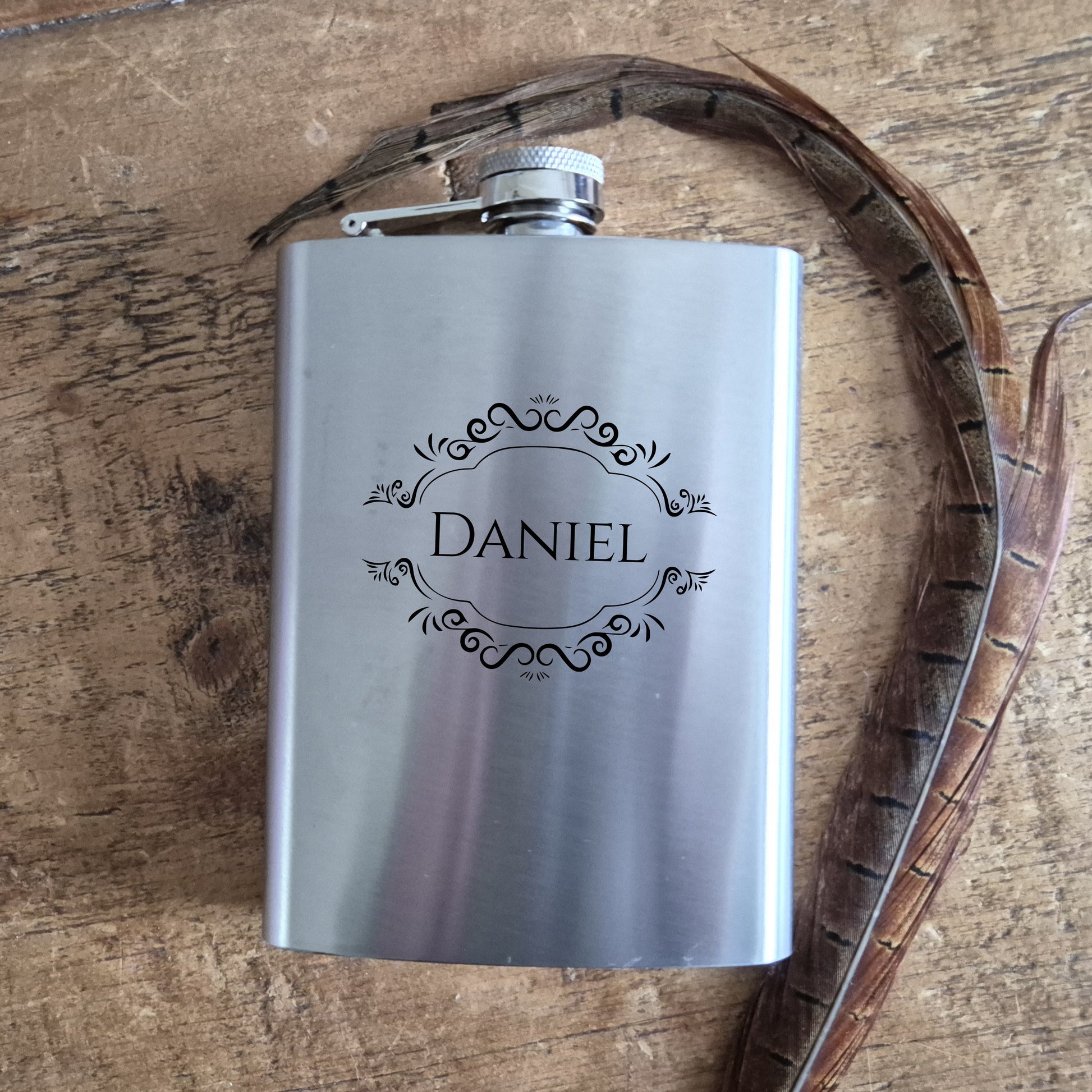 Silver flask with 'Daniel' engraving on a wooden surface