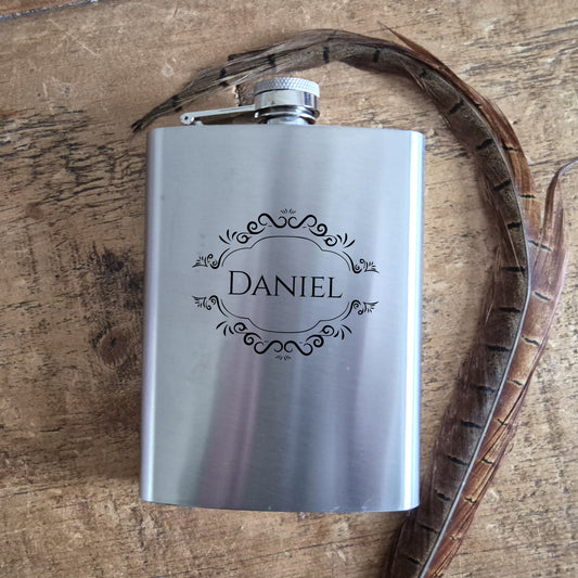 Silver flask with 'Daniel' engraving on a wooden surface